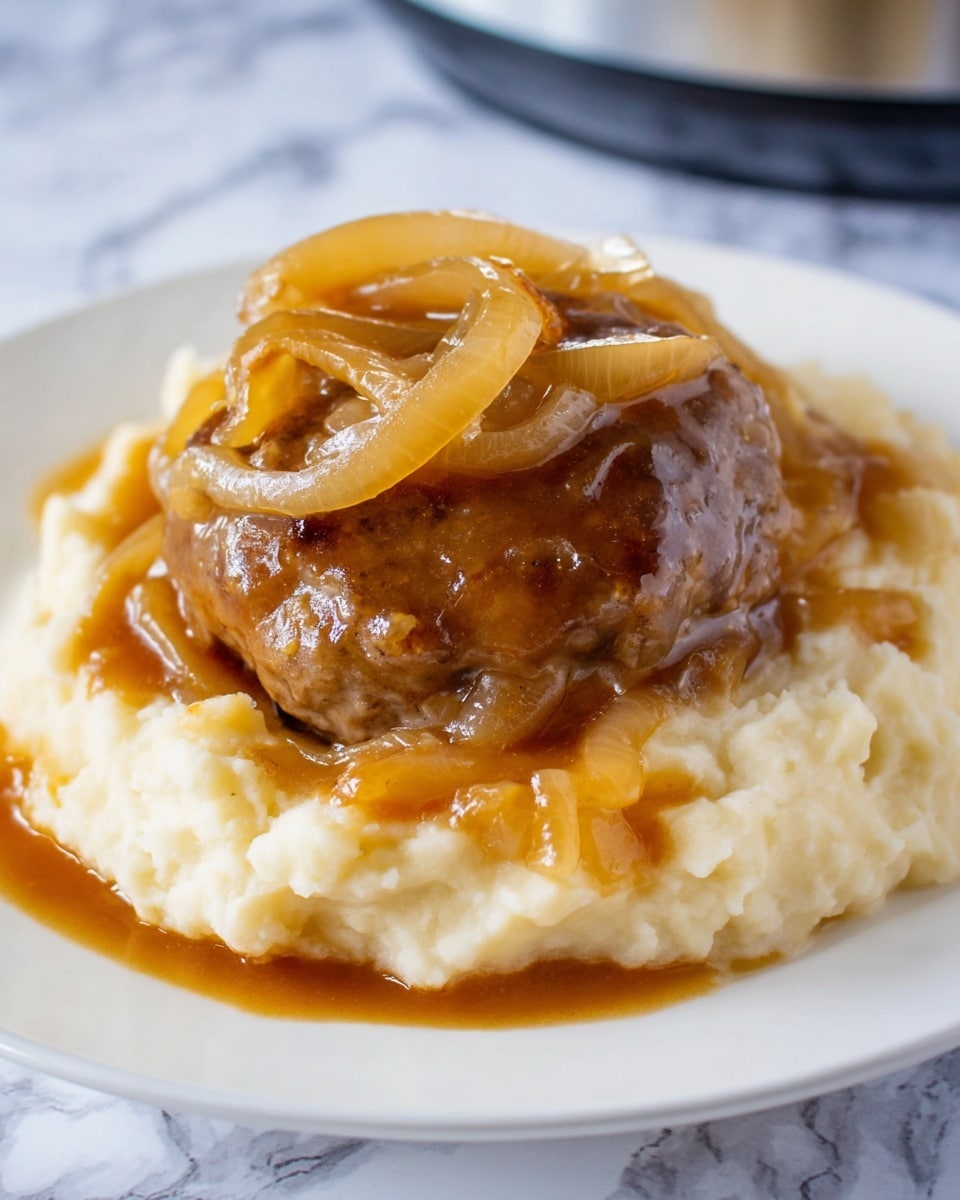 This image shows a white plate with three main layers of food. The bottom layer is creamy mashed potatoes, light beige in color with a smooth and slightly chunky texture. On top of this is a round brown meat patty, glazed with brown gravy that looks shiny and a bit thick. The top layer has caramelized onions, light golden in color, soft with a slightly translucent look, draped over the meat and covered in the gravy that spills over onto the mashed potatoes. The plate rests on a white marbled surface. photo taken with an iphone --ar 4:5 --v 7