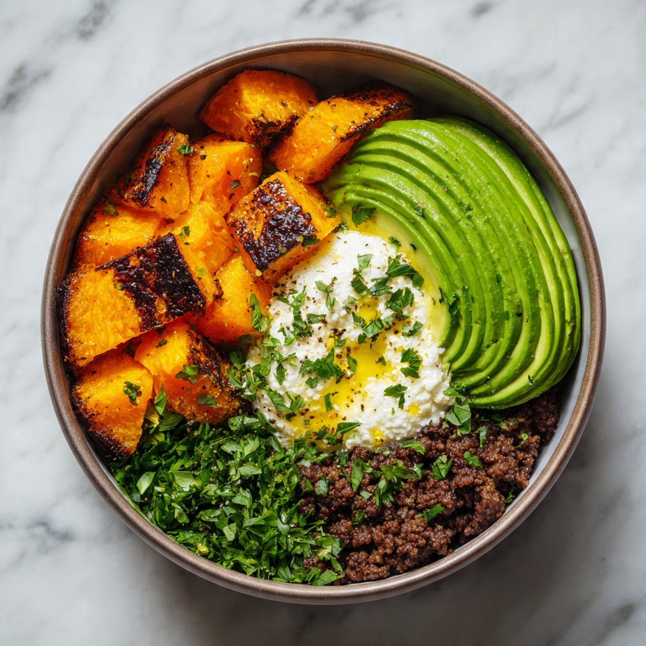 A round bowl contains four layers arranged separately: bright orange roasted pumpkin chunks with a slightly charred texture cover the left side, thin slices of green avocado with a smooth texture fan out neatly on the top right, a creamy dollop of white cottage cheese with a drizzle of golden oil and sprinkled green herbs sits in the middle, and dark brown cooked ground meat forms the bottom layer on the right side. Fresh green chopped herbs are sprinkled over all layers. The bowl sits on a white marbled surface. photo taken with an iphone --ar 4:5 --v 7