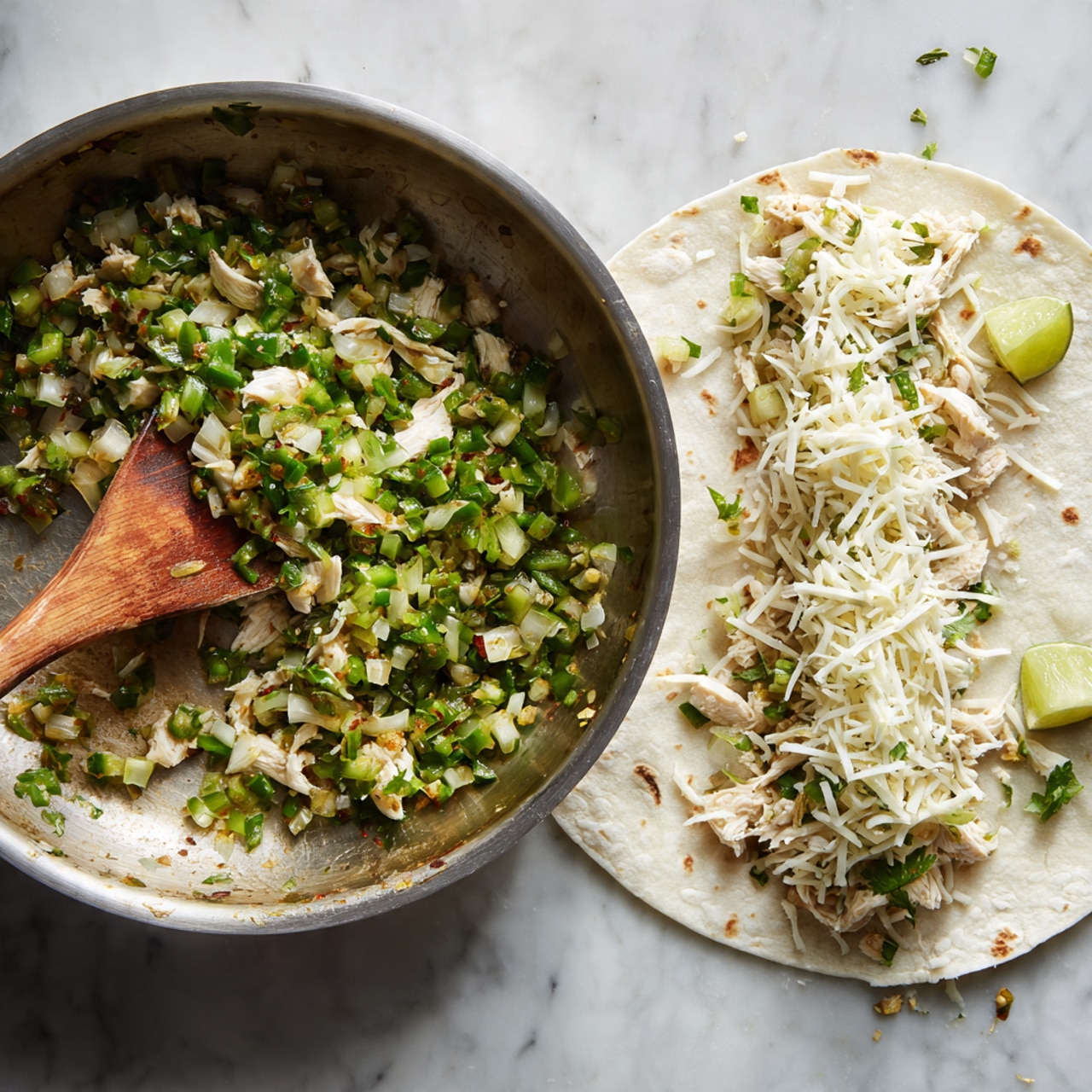 The image shows two parts: on the left, a shiny metal pan filled with a mix of small chopped green chilies, white onions, and green herbs being stirred with a wooden spatula. On the right, a white tortilla lays flat on a white marbled surface, covered with the same cooked mixture spread in a horizontal strip, topped with shredded white chicken and a generous layer of white shredded cheese. A wedge of lime is placed near the top edge of the tortilla, and some small bits of herbs and cheese are scattered around. Photo taken with an iphone --ar 4:5 --v 7