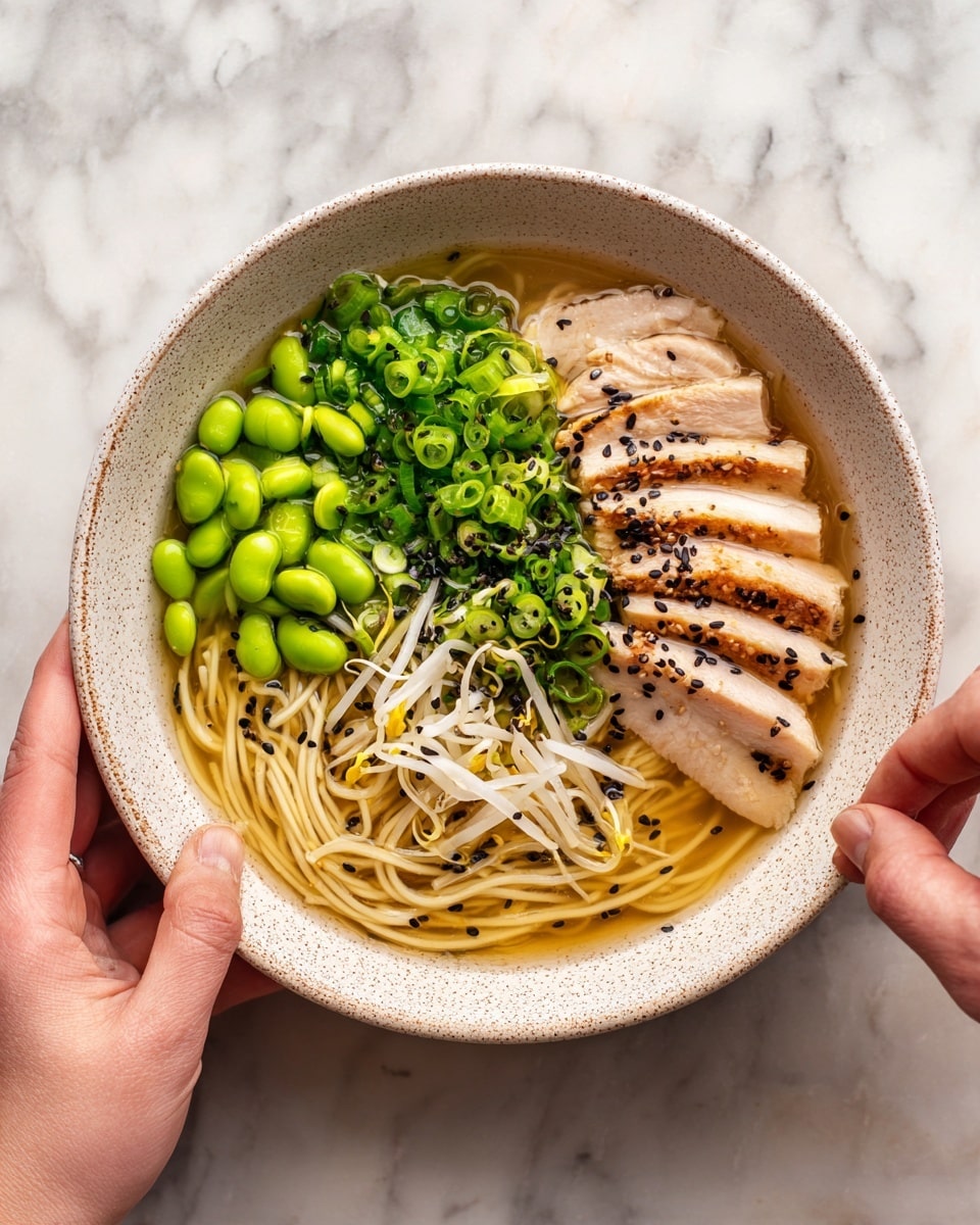 A bowl with light tan broth filled with thin, pale yellow noodles in the center. On the top right side, there are several slices of light brown cooked chicken with a slightly crispy texture. The top left has bright green sliced spring onions, and the bottom left has shiny green edamame beans. Towards the bottom middle, light beige bean sprouts are being added by a woman's hand. Small black sesame seeds are scattered over the dish. The bowl sits on a white marbled surface. Photo taken with an iphone --ar 4:5 --v 7