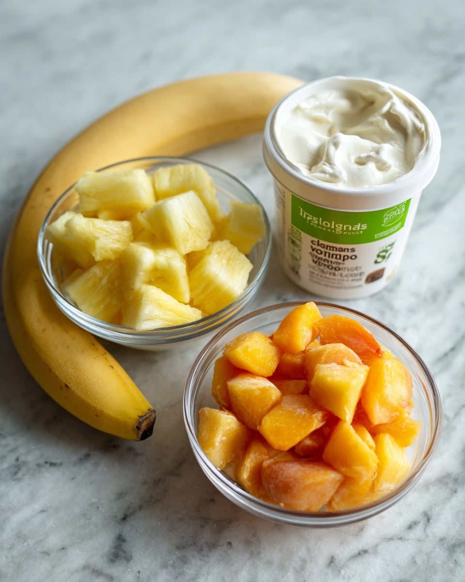A white container of Icelandic Provisions extra creamy vanilla yogurt sits near a small clear bowl of yellow frozen pineapple chunks and a larger clear bowl filled with orange frozen peach slices. Next to the bowls is a peeled banana, white and smooth in texture. Behind the fruit and yogurt is a small green-labeled jar of 365 organic ground cinnamon. All items are placed on a white marbled textured surface. photo taken with an iphone --ar 4:5 --v 7