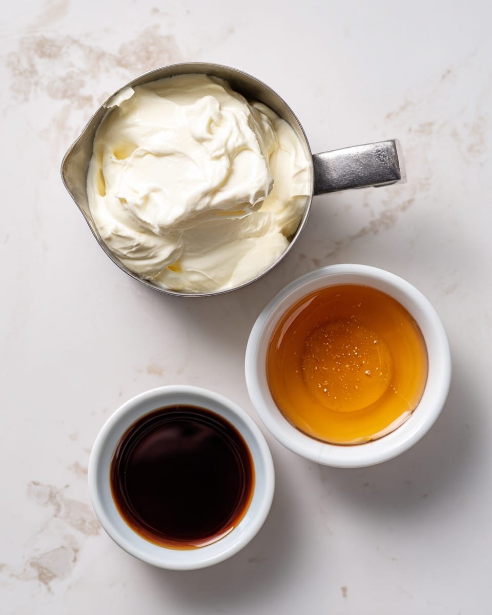 The image shows three small white containers placed on a white marbled surface. The first item is a metal measuring cup filled with a thick, creamy white substance, likely yogurt or cream, with visible soft peaks and smooth texture, positioned at the top left. To the right, there's a small white bowl containing a golden amber liquid, probably honey, with a smooth surface and a few tiny bubbles. Below these, on the left side, is an even smaller white bowl filled with a dark brown liquid, possibly vanilla extract, with a glossy finish. The arrangement is clean and simple, emphasizing the different colors and textures of the ingredients. photo taken with an iphone --ar 4:5 --v 7