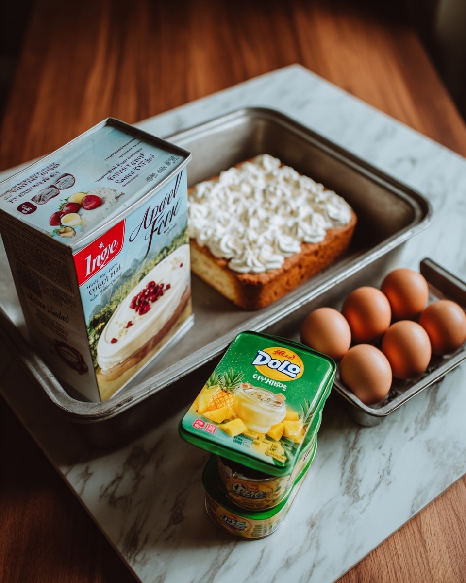 The image shows a silver baking tray filled with baking ingredients placed on a dark wooden surface with a white marbled texture. Inside the tray, there is a box of Angel Food cake mix leaning on the left side, showing a picture of the cake topped with white frosting and a few red berries. Next to the box are four brown eggs arranged in two rows of two on the right. In front of the box and eggs, there is a can of Dole crushed pineapple lying on its side with a bright label showing a pineapple and yellow chunks. To the right of the can, two stacked green boxes of Jell-O pistachio instant pudding are visible, with images of creamy green pudding on the packaging. The scene has a soft natural light and a warm tone. Photo taken with an iphone --ar 4:5 --v 7