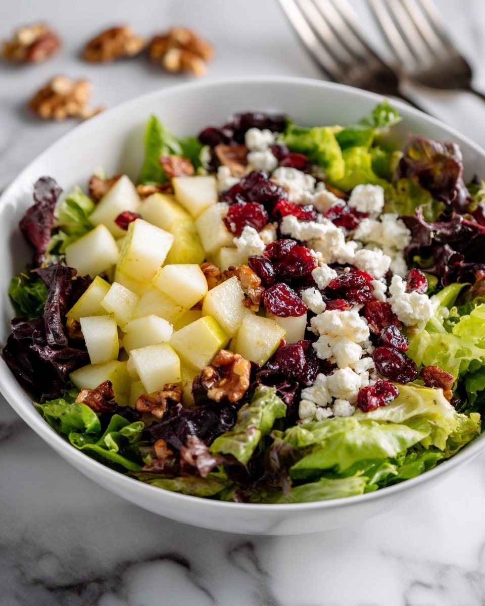 A white bowl filled with a fresh salad sits on a white marbled surface. The salad has three main layers: the bottom layer is a mix of dark and light green leafy lettuce. The middle layer consists of light green and pale yellow pear pieces, cut into small cubes scattered evenly. On top, there are small white crumbles of cheese, bright red dried cranberries, and chunks of brown walnuts. Some salad ingredients and forks are visible around the bowl. Photo taken with an iphone --ar 4:5 --v 7