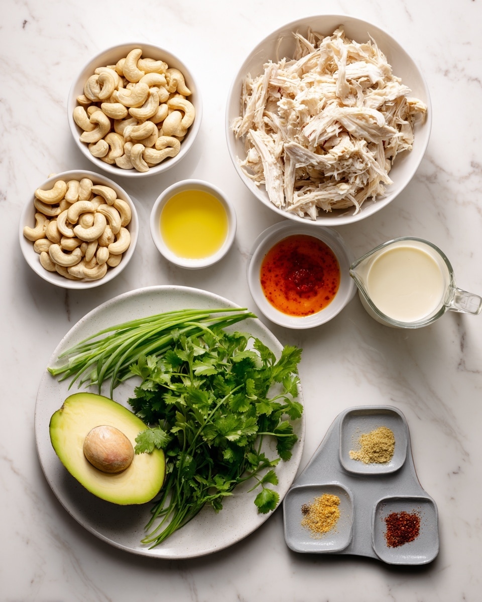 The image shows several white bowls and a plate arranged on a white marbled surface. The largest white bowl contains shredded light beige chicken meat. Next to it is a medium white bowl filled with beige cashew nuts. On a white plate, there is a dark green avocado lying on top of fresh green herbs, including cilantro and chives. Smaller white bowls hold various ingredients: one has a bright orange-red sauce, another contains a pale yellow powder, and a third has a clear yellow liquid. There is also a glass measuring cup with a white creamy liquid, and a small gray dish with four small piles of different spices in red, light brown, beige, and white. photo taken with an iphone --ar 4:5 --v 7