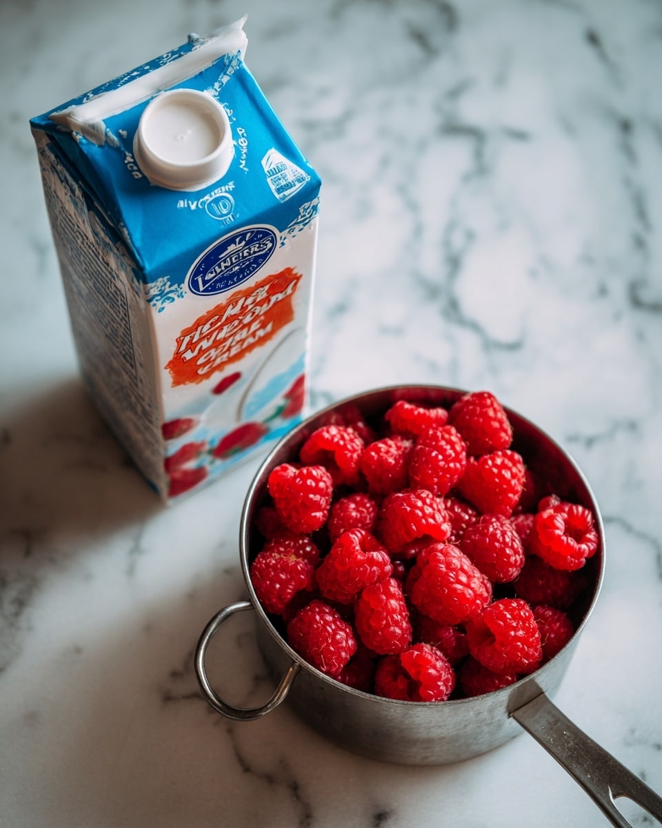 The image shows a carton of Lucerne Dairy Farms Heavy Whipping Cream on the left, with white, blue, and orange colors and text on the carton. To the right of the carton, there is a metal measuring cup filled to the top with bright red frozen raspberries. Both items are placed on a white marbled surface. Photo taken with an iphone --ar 4:5 --v 7