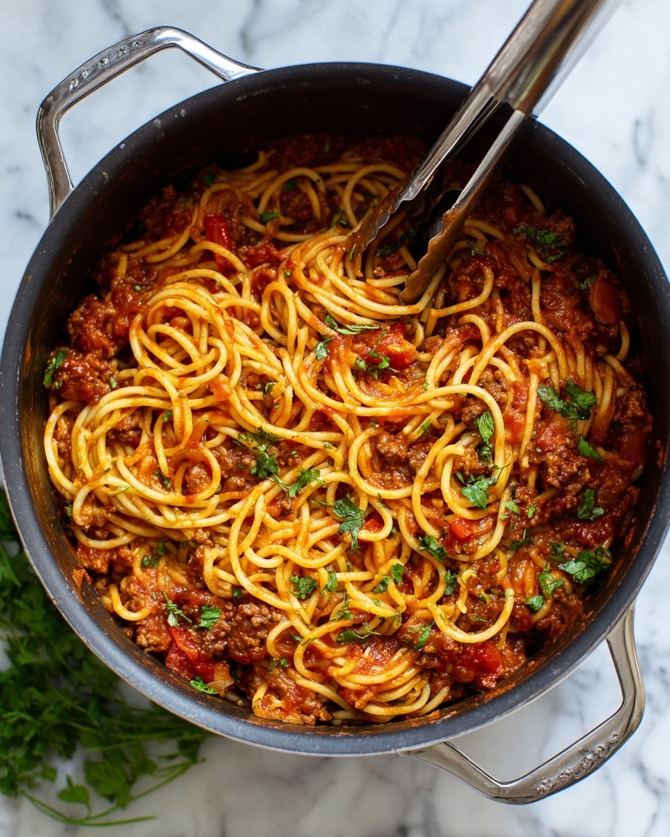Inside a black cooker with a silver inner pot, tangled spaghetti noodles are mixed with thick red tomato sauce and bits of browned meat, giving the dish a hearty texture. The noodles are coated well in the sauce and topped with scattered green herb leaves for a fresh touch. A silver pair of tongs rests inside, ready to serve. The cooker sits on a white marbled surface with some green leafy herbs around. photo taken with an iphone --ar 4:5 --v 7