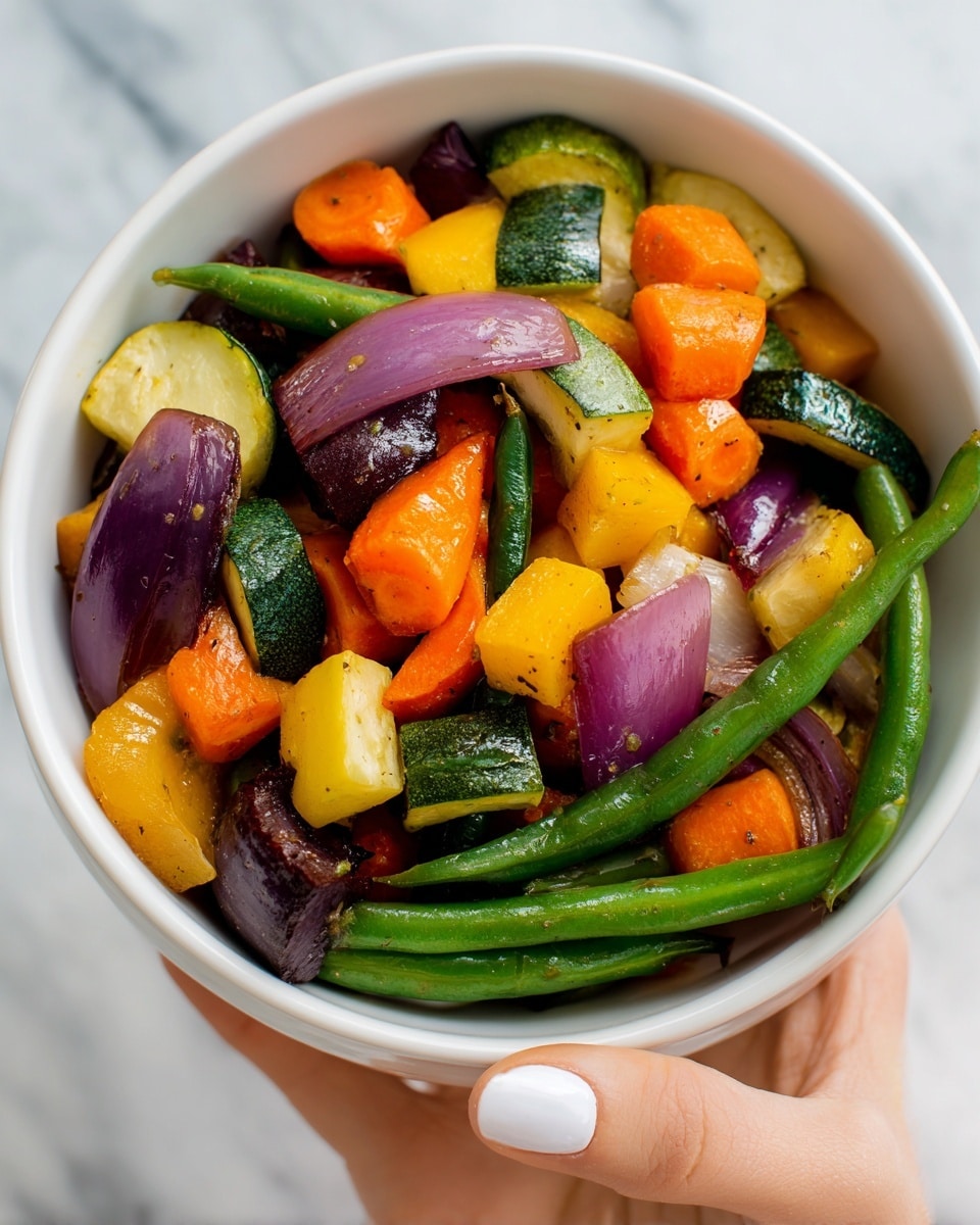 A white bowl filled with a colorful mix of cooked vegetables held by a woman's hand with white nail polish; the vegetables are layered loosely with green beans at the bottom, followed by chunks of orange carrots, yellow squash, dark purple eggplants, green zucchini, and purple-red onion slices, all showing a slightly glossy texture from cooking; the background is a soft white marbled surface and the bowl is held near the center of the image photo taken with an iphone --ar 4:5 --v 7