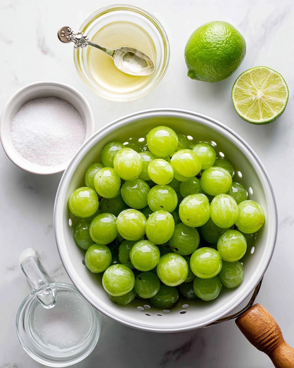 A white colander filled with one pound of green grapes sits in the center on a white marbled surface. At the top right corner. Above the colander is a halved lime showing its inside texture, and next to it is a small clear bowl with one tablespoon of lime juice and a tarnished silver spoon resting inside. On the bottom left, there is a small white bowl filled with half a cup of sugar, showing a soft, powdery texture, and on the bottom right, a clear glass measuring cup with three ounces of vodka, featuring a wooden handle. The scene is bright and clear, with the items neatly arranged. Photo taken with an iphone --ar 4:5 --v 7