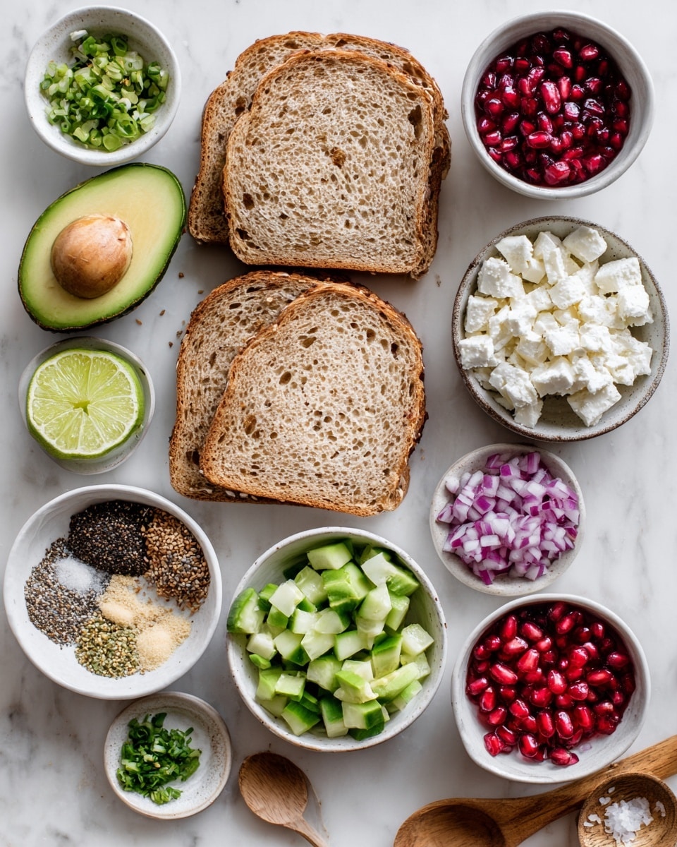 The image shows a clean arrangement of sandwich ingredients on a white marbled surface. In the center are two slices of whole grain bread with a light brown, grainy texture. Above the bread, there are two avocado halves, one with a light green flesh and the other showing the brown seed. To the left of the bread, lime wedges are placed next to a small white bowl filled with everything bagel seasoning, which is a mix of black, white, and brown seeds and flakes. Below them, a white bowl holds diced light green cucumber pieces, while another white bowl contains deep red pomegranate seeds. To the right of the bread, a small white bowl has chopped green chives and light purple diced red onions together. Below this bowl, another white bowl has bright red diced red bell peppers. Further right, a rustic white plate holds crumbled white feta cheese. Near the top right corner, a small wooden bowl contains a mix of white salt and black pepper, and below it lies a wooden spoon with light beige garlic powder. The entire setting is bright and fresh looking. photo taken with an iphone --ar 4:5 --v 7
