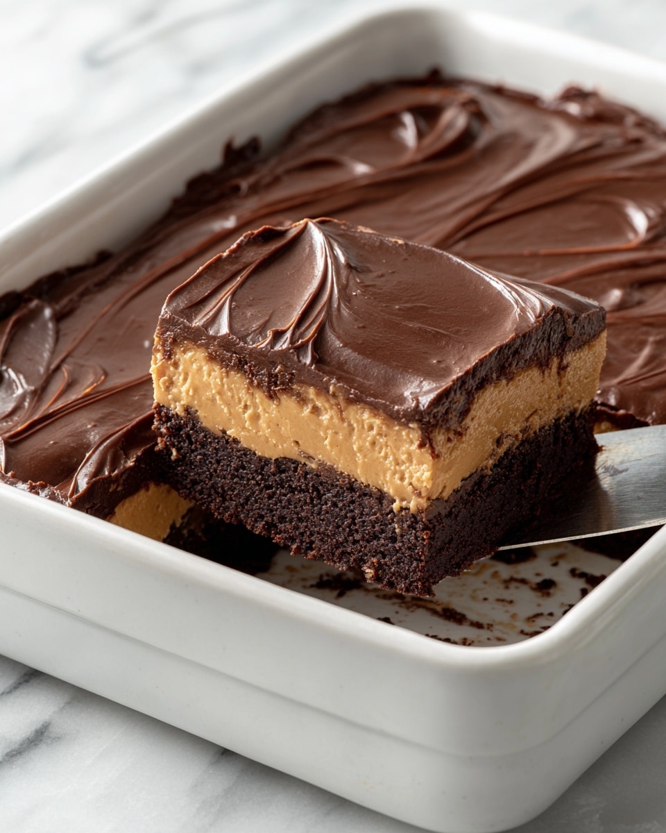 A close-up image of a three-layer dessert in a white baking dish on a white marbled surface. The bottom layer is a dark brown brownie with a soft texture. The middle layer is a thick, smooth, light brown peanut butter-like filling. The top layer is a glossy, rich, dark chocolate ganache with visible swirls and a shiny finish. A piece has been cut and partially lifted with a silver spatula, showing the clean separation of layers. The surface inside the baking dish has some crumbs scattered on the white marbled texture. photo taken with an iphone --ar 4:5 --v 7