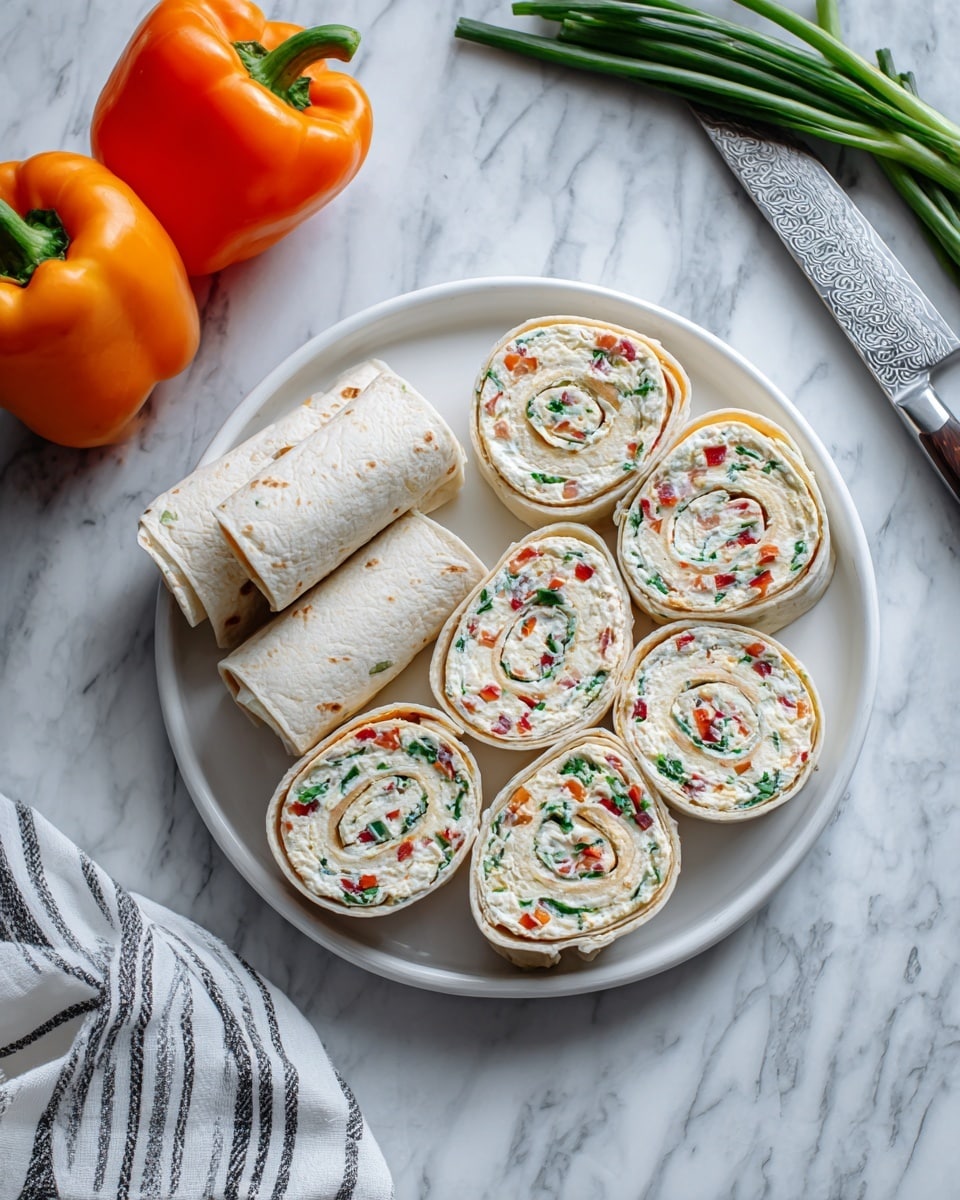 The image shows a white round plate on a white marbled surface, with two whole rolled tortillas on the left side of the plate and several pinwheel slices arranged on the right side. Each pinwheel slice reveals layers of white tortilla filled with a creamy white spread mixed with small pieces of red and green vegetables, creating a colorful swirl pattern. To the left of the plate, two bright orange bell peppers rest on the marbled surface, and on the top right, a silver knife with a patterned blade and a few green onions are partially visible. A white towel with black stripes lies at the bottom right corner. photo taken with an iphone --ar 4:5 --v 7
