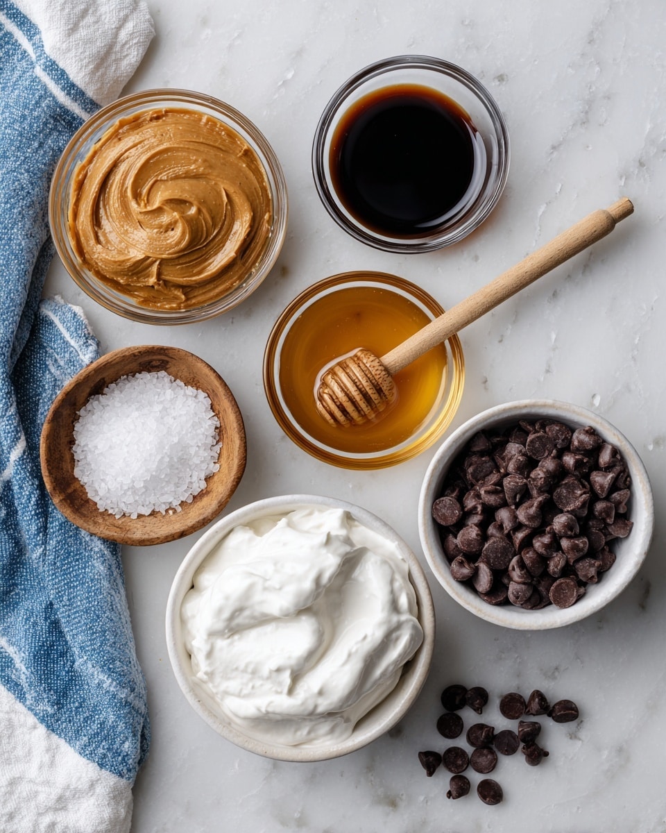 This image shows seven small clear glass bowls and one white bowl placed on a white marbled surface. In the top left, there is a bowl with a smooth light brown peanut butter. Beside it to the right is a small bowl with dark brown vanilla extract. Below those, on the left, is a tiny wooden bowl filled with coarse white sea salt, and slightly to the right is a clear bowl with golden honey, with a wooden honey dipper resting inside it. At the bottom center is a white bowl filled with thick, creamy white Greek yogurt, and to the right of it is a white bowl filled with dark brown chocolate chips. Some chocolate chips are scattered on the surface around the bowls. The image corners show part of a blue and white striped cloth on the left side. photo taken with an iphone --ar 4:5 --v 7