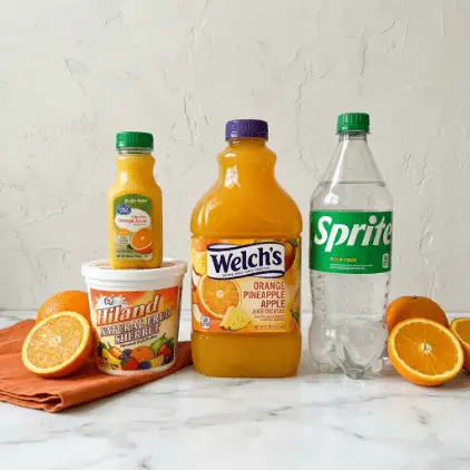 The image shows four main items arranged in a row on a white marbled surface with a light textured wall background. From left to right, there is an orange fabric folded beneath a white tub of Hiland Natural Fruit Sherbet that has a colorful fruit label. On top of this tub sits a small green-capped container of Great Value pulp-free orange juice. Next to it is a large plastic bottle of Welch's Orange Pineapple Apple Juice Cocktail, filled with bright orange liquid and topped with a purple cap. On the far right stands a clear plastic bottle of Sprite with a green label and cap, partially filled with clear liquid. Fresh orange halves and whole oranges are placed around these items, two on the left side and two on the right, adding a pop of bright orange color. photo taken with an iphone --ar 4:5 --v 7