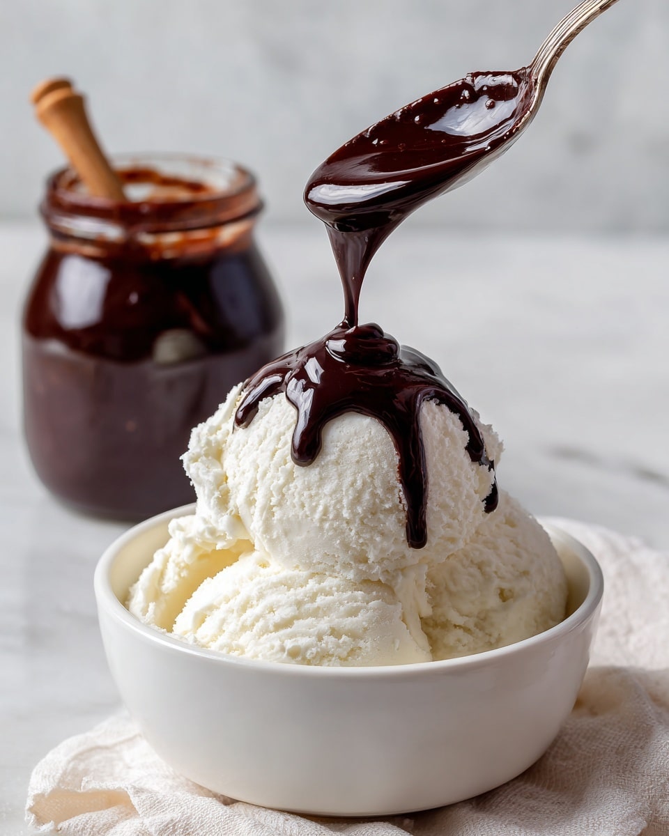 A small white bowl filled with one large scoop of white creamy ice cream with soft, smooth texture. A spoon held above the ice cream drizzles a thick, dark brown chocolate sauce that flows down the scoop gently. In the blurry background, an open jar filled with the same dark chocolate sauce is visible, sitting on a white marbled surface. The scene is bright with soft, natural light, highlighting the rich contrast between the white ice cream and the dark sauce photo taken with an iphone --ar 4:5 --v 7