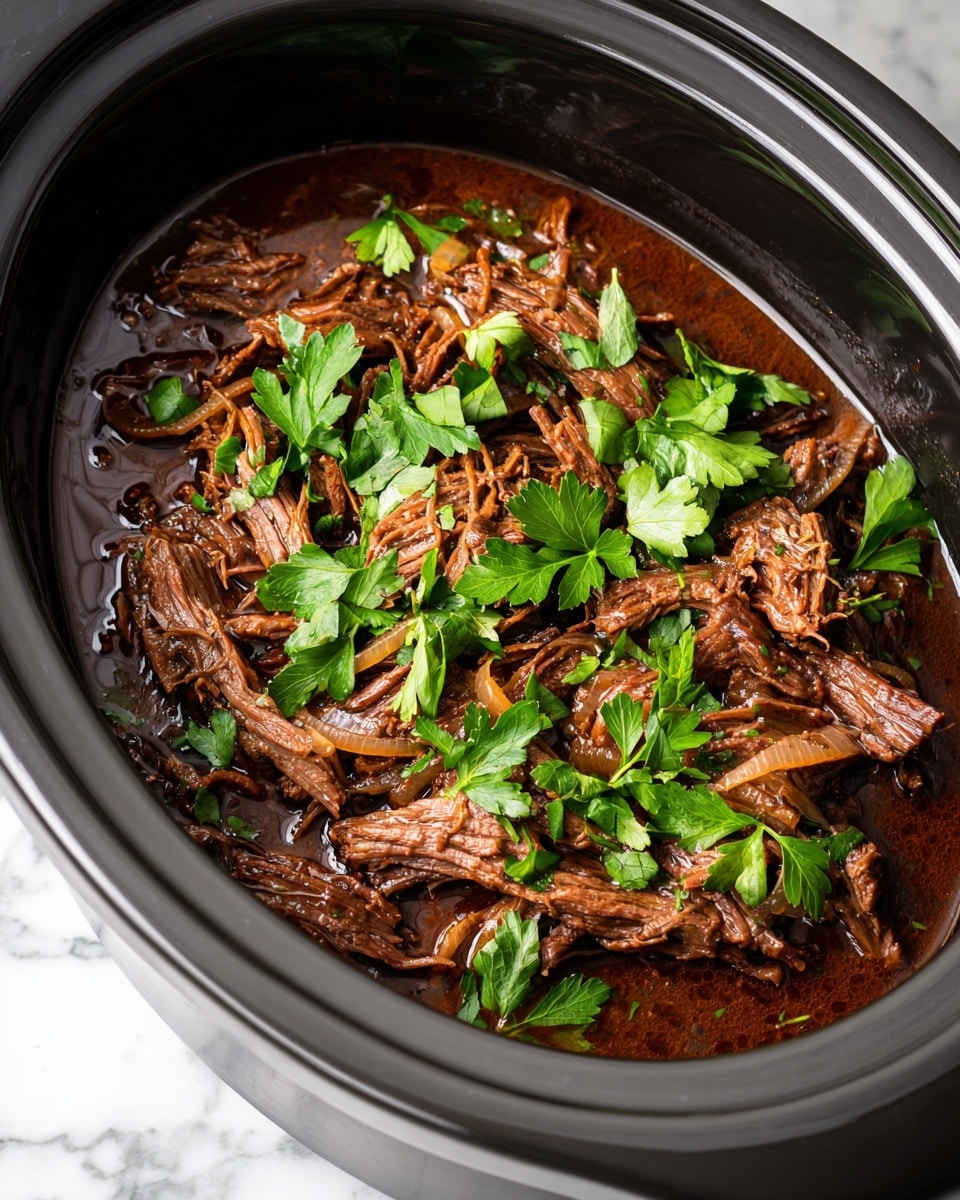 This image shows a close-up of a slow cooker filled with shredded brown meat in thick dark brown sauce. The meat appears tender and mixed with soft, light brown cooked onion slices. Bright green parsley leaves are scattered on top, adding some fresh color contrast. The inside rim of the gray slow cooker is visible around the food. The photo is placed on a white marbled surface. photo taken with an iphone --ar 4:5 --v 7