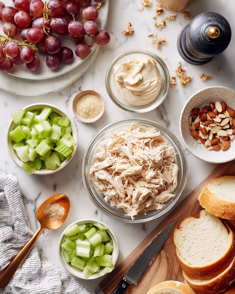 The image shows several clear and white bowls on a white marbled surface, each with different ingredients arranged neatly. At the center bottom is a clear bowl filled with light beige shredded chicken. To the left is a small white bowl with bright green celery pieces sitting on a white and navy striped cloth next to an orange-tinted spoon with creamy, pale mayonnaise. Above the chicken bowl, there is a small clear bowl filled with light brown sliced almonds, and next to it on the right is another small clear bowl containing light tan celery salt with a golden spoon. At the top left, there is a white plate with dark red grapes, some of which are halved, and clusters of whole grapes sit nearby. To the right of the grapes is a tall black and clear pepper grinder. On the top right, a white plate holds four soft, light brown bread slices with a fine crust. A wooden cutting board rests at the lower right corner with whole and sliced celery and a knife placed on top. A woman's hand holds the knife. photo taken with an iphone --ar 4:5 --v 7