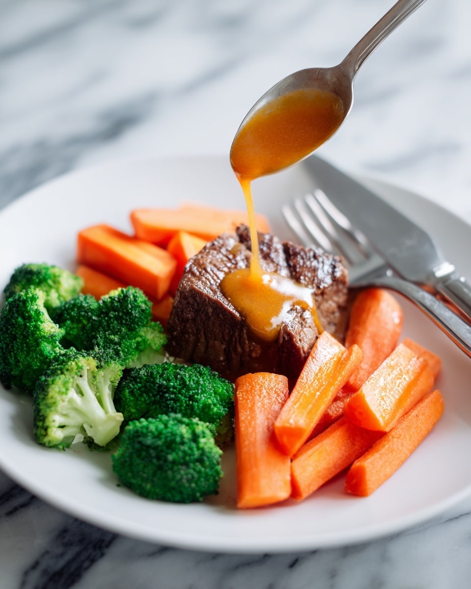 A white plate holds a meal with one cooked piece of meat in the center, dark brown and crispy on the edges. Around the meat are thick carrot sticks that are orange and soft looking. Bright green steamed broccoli pieces are spread around the carrots and meat. An orange sauce is being poured over the meat from a spoon, with some sauce also on the carrots and broccoli. The background is a white marbled surface, and silver fork and knife rest to the right of the plate. Photo taken with an iphone --ar 4:5 --v 7
