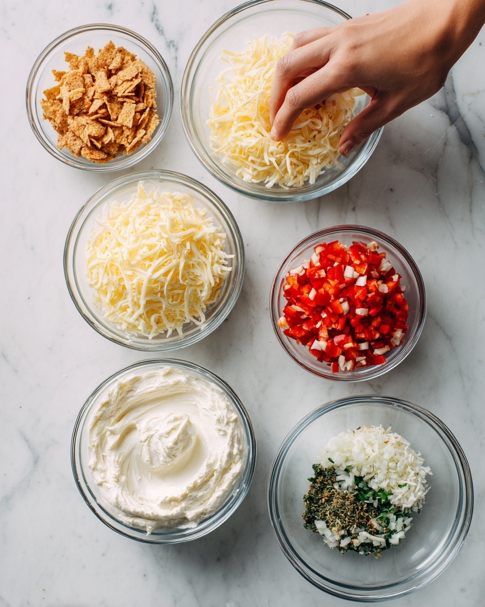 The image shows five clear glass bowls arranged on a white marbled surface. The largest bowl at the bottom left contains smooth, white cream cheese. To its right, a slightly smaller bowl is filled with shredded yellow and white cheese. Above these, a medium bowl holds bright red chopped red peppers with some small bits of white inside. To the upper right, a small bowl contains a mix of white and green chopped herbs. To the upper left, a small bowl is filled with finely crushed crackers that are light brown in color. A woman's hand is reaching from the left side, touching the bowl with cream cheese. Photo taken with an iphone --ar 4:5 --v 7